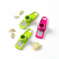 Green and pink garlic grater press flat lay with fresh garlic cloves white background