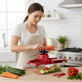 Woman using red mandoline slicer to slice carrots and zucchini in modern kitchen lifestyle